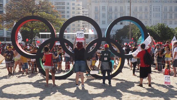 Manifestantes erguem cartazes contra Temer atrás do símbolo dos arcos olímpicos, onde os turistas tiram fotos - Sputnik Brasil