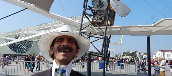 Homem fantasiado de Santos Dumont em frente à réplica do 14-Bis - Sputnik Brasil