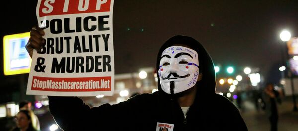 A protestor wearing a Guy Fawkes mask holds a sign as demonstrators march through the streets of Ferguson, Missouri, March 12, 2015 - Sputnik Brasil