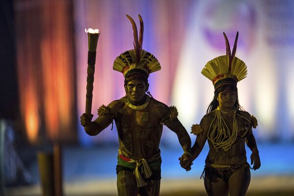 Um homem e uma mulher indígenas passam com a tocha de inauguração dos Jogos Mundiais Indígenas em Palmas, Tocantins, em 23 de outubro de 2015 - Sputnik Brasil