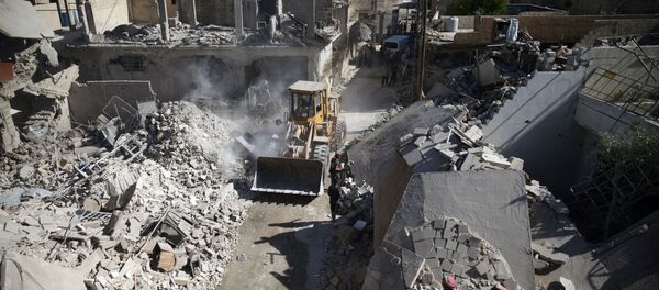 A front loader remove debris from a site hit by an airstrike in the rebel held Douma neighborhood of Damascus (File) - Sputnik Brasil