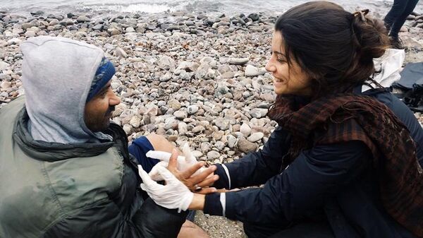 Gabriela Shapazian auxiliando um refugiado - Sputnik Brasil