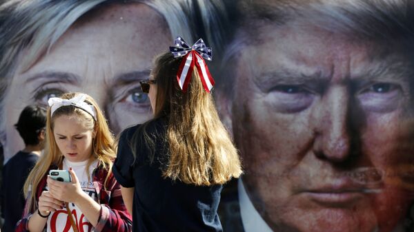 Pessoas aguardam ao lado de um ônibus adornado com fotos dos então candidatos à presidência dos EUA, Hillary Clinton e Donald Trump, em 2016 - Sputnik Brasil