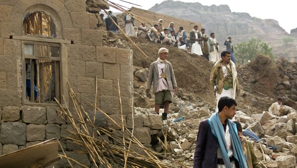 Iemenitas andam sobre destroços de casas destruidas pelos bombardeios sauditas perto da capital Sanaa - Sputnik Brasil