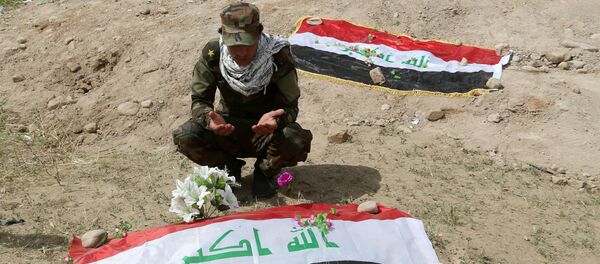 Um miliciano xiita reza em frente a uma cova onde se acredita estar o corpo de um soldado iraquiano. - Sputnik Brasil