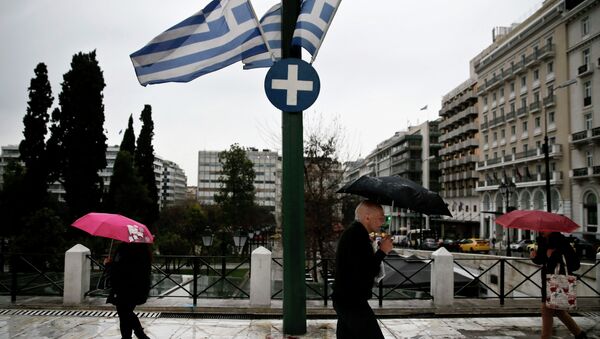People holding umbrellas make their way next to fluttering Greek national flags on the main Constitution (Syntagma) square during heavy rainfall in Athens - Sputnik Brasil