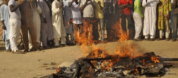 Multidão acompanha um pedaço de carro em chamas após uma explosão em 28 de novembro de 2014 em Kano, Nigéria; o local tinha sido alvejado pelo Boko Haram - Sputnik Brasil