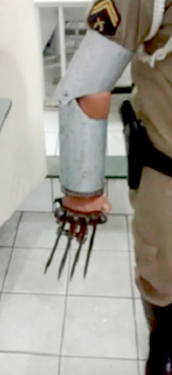 Um policial demostra como a armadura artesanal com as garras foi usada - Sputnik Brasil