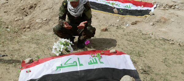 Shiite militiaman prays at a mass grave - Sputnik Brasil