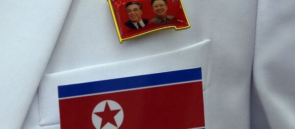 Broche com as imagens de Kim Il Sung e Kim Jong Il, respectivamente, fundador e atual líder da Coreia do Norte, junto à bandeira do país. Broche com as imagens de Kim Il Sung e Kim Jong Il, respectivamente, fundador e atual líder da Coreia do Norte, junto à bandeira do país. - Sputnik Brasil