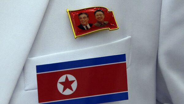 Broche com as imagens de Kim Il Sung e Kim Jong Il, respectivamente, fundador e atual líder da Coreia do Norte, junto à bandeira do país. - Sputnik Brasil