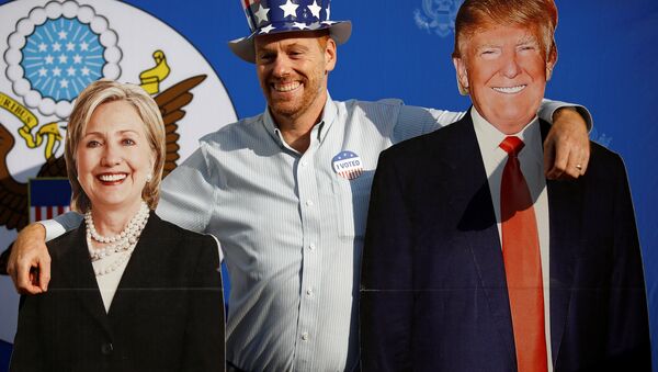 Um homem posa ao ser fotografado junto às figuras de papelão dos candidatos à presidência norte-americana, Hillary Clinton e Donald Trump  - Sputnik Brasil
