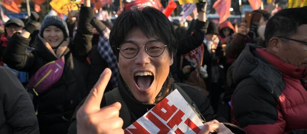 Um manifestante reage após o impeachment bem sucedido do parlamento sul-coreano da presidente Park Geun-hye enquanto multidões se juntam fora da Assembleia Nacional em Seoul em 9 de dezembro de 2016. - Sputnik Brasil