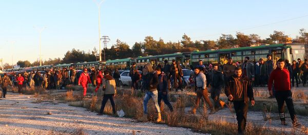 Os evacuados do leste de Aleppo desembarcam dos ônibus após sua chegada à cidade de al-Rashideen, que é mantida pelos insurgentes, na Síria, em 15 de dezembro de 2016. - Sputnik Brasil