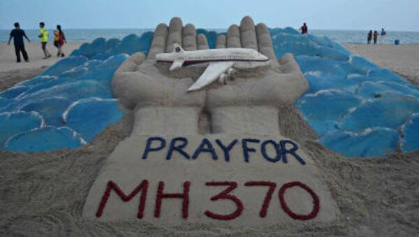 Banhistas passam por escultura de areia com mensagem de orações pelo voo perdido da Malaysian Airlines MH370 - Sputnik Brasil