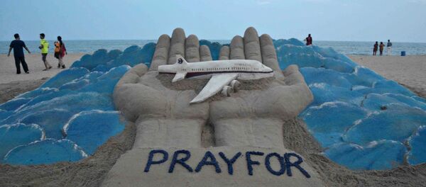 Beachgoers walk past a sand sculpture made by Indian sand artist Sudersan Pattnaik with a message of prayers for the missing Malaysian Airlines flight MH370 - Sputnik Brasil