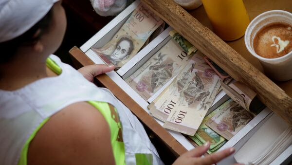 Um caixa recebe notas venezuelanas de bolívar em um mercado no centro de Caracas, Venezuela - Sputnik Brasil