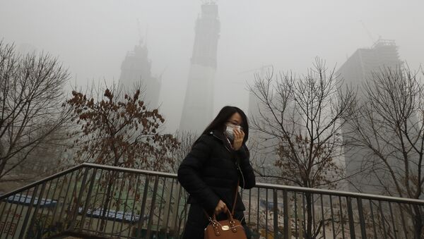 Uma mulher de máscara para a proteção contra a poluição do ar anda em uma ponteem Beijing enquanto a capital de China é encoberta pela fumaça pesada na terça-feira, dezembro 20, 2016 - Sputnik Brasil