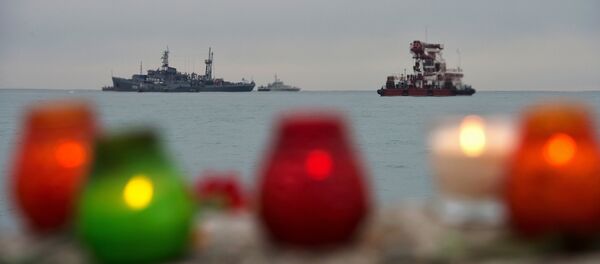 Velas em homenagem às vítimas da queda do avião russo. Ao fundo, navios da Marinha russa realizam busca dos escombros do Tu-154 no mar Negro, Rússia, 27 de dezembro de 2016 - Sputnik Brasil