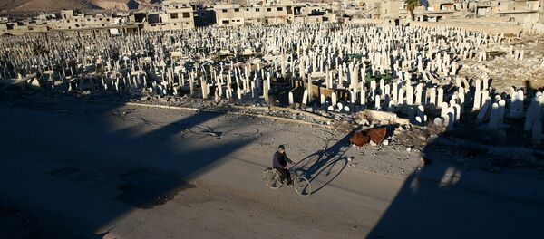Civil anda de bicicleta ao lado de cemitério em Douma, ocupada por rebeldes, nos arredores de Damasco, Síria, 3 de janeiro de 2017 - Sputnik Brasil