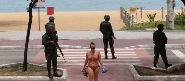 Uma mulher cruza uma via pública, guardada por soldados das Forças Armadas em Vitória, ES, em 8 de fevereiro - Sputnik Brasil