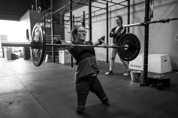 Imagem da série Atleta Adaptável, de Darren Calabrese, que mostra a lutadora Lindsay treinando com ajuda de correntes e fitas para levantamento terra sob olho vigilante da sua técnica Jenny Jeffries - Sputnik Brasil