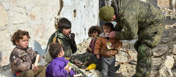 Engenheiros militares do centro internacional de desminagem do Exército russo continuam a operação no leste de Aleppo, na Síria. Foto mostra um soldado russo junto a crianças sírias - Sputnik Brasil