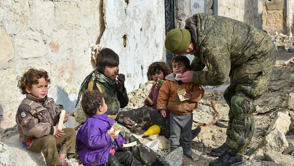 Engenheiros militares do centro internacional de desminagem do Exército russo continuam a operação no leste de Aleppo, na Síria. Foto mostra um soldado russo junto a crianças sírias - Sputnik Brasil