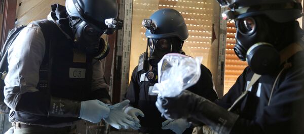 A U.N. chemical weapons expert, wearing a gas mask, holds a plastic bag containing samples from one of the sites of an alleged chemical weapons attack in the Ain Tarma neighbourhood of Damascus, Syria. (File) A U.N. chemical weapons expert, wearing a gas mask, holds a plastic bag containing samples from one of the sites of an alleged chemical weapons attack in the Ain Tarma neighbourhood of Damascus, Syria. (File) - Sputnik Brasil