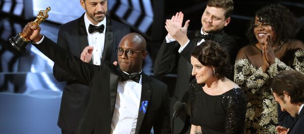 89th Academy Awards - Oscars Awards Show - Hollywood, California, U.S. - 26/02/17 - Writer and Director Barry Jenkins of Moonlight holds up the Best Picture Oscar in front of host Jimmy Kimmel (rear) as he stands with Producer Adele Romanski (R). - Sputnik Brasil