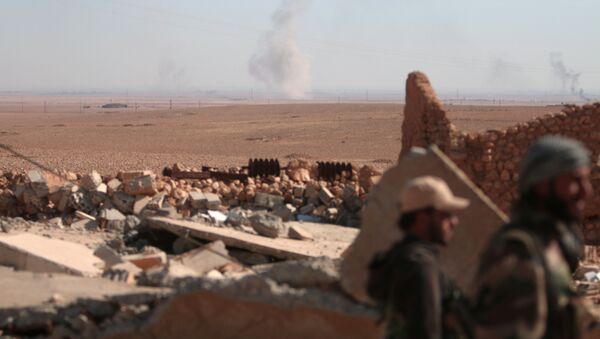 Smoke rises in the background as Syrian Democratic Forces (SDF) fighters stand near rubble of a destroyed building, north of Raqqa city, Syria - Sputnik Brasil