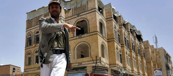 Um homem indica ao fotógrafo as consequências de um ataque aéreo da coalizão saudita no Iêmen - Sputnik Brasil