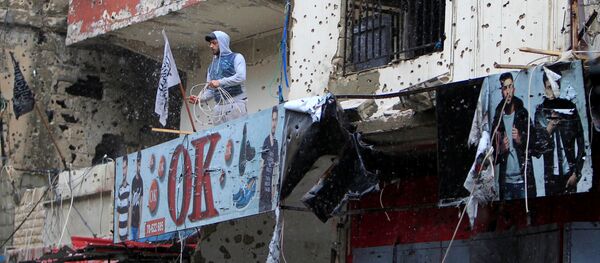 Homem na varanda de um dos edifícios com marcas de bombardeios em um campo de refugiados na Líbia (Arquivo) - Sputnik Brasil