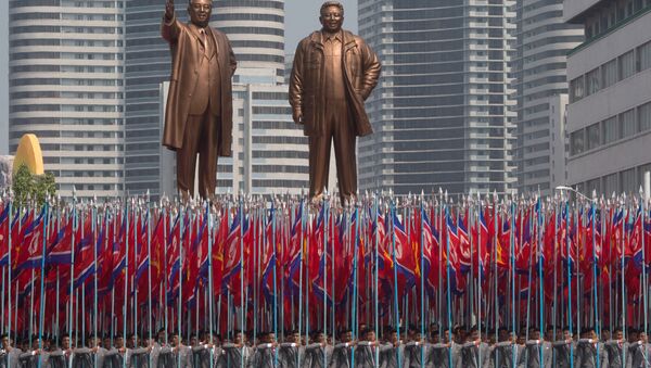 Participantes dos festejos comemorando os 105 anos de nascimento de Kim Jong-il são vistos com bandeiras na praça principal em Pyongyang - Sputnik Brasil