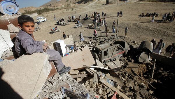 Um menino olha para a câmera enquanto se senta nos destroços de uma casa destruída por um ataque aéreo liderado pelos sauditas nos arredores de Sanaa, Iêmen. - Sputnik Brasil