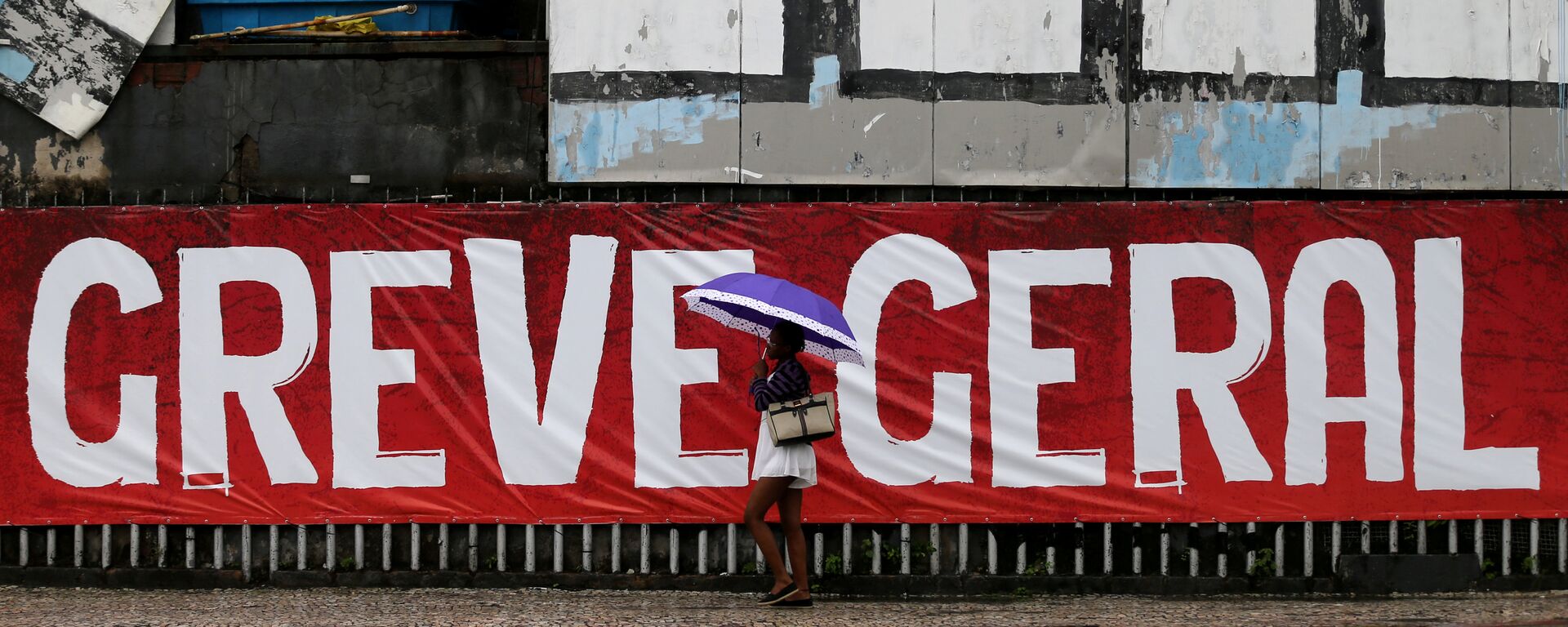 Uma mulher passa na frente de uma parede com a inscrição Greve Geral no Rio de Janeiro em 28 de abril de 2017 - Sputnik Brasil, 1920, 13.01.2022