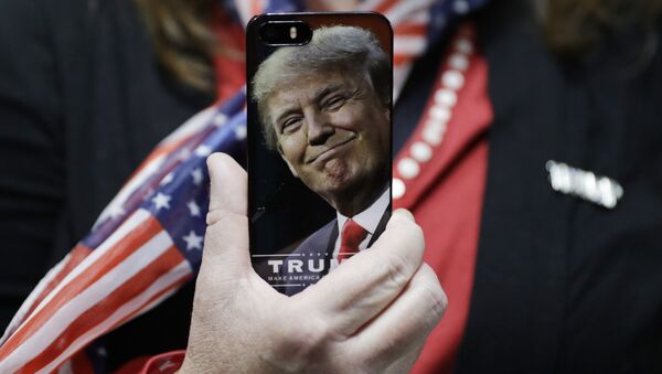 Mulher segura celular com a foto de Donald Trump - Sputnik Brasil