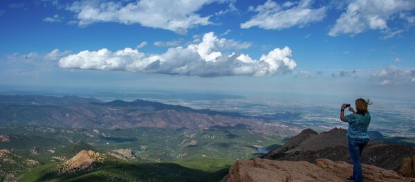 A woman takes a picture at the top of Pikes Peak mountain in the Front Range of the Rocky Mountains within Pike National Forest, 10 miles (16 km) west of Colorado Springs, Colorado, on June 08,2013 - Sputnik Brasil