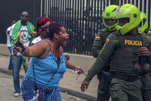 Mulher com ferimentos discute com polícia durante protestos na Colômbia - Sputnik Brasil