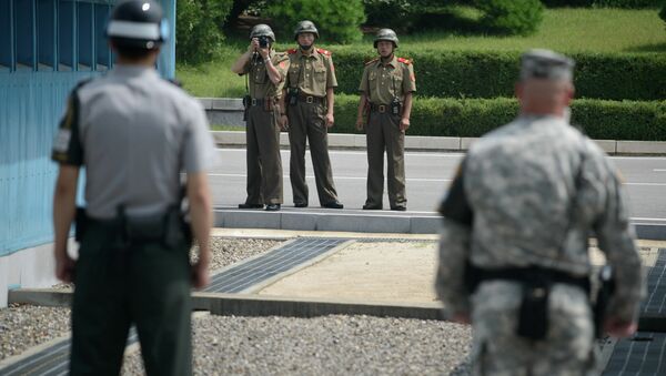 Soldados norte-coreanos tiram fotos de soldado sul-coreano e  de militar norte-americano junto à linha de demarcação que separa as duas Coreias (foto de arquivo) - Sputnik Brasil