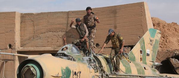 Combatentes das Forças Democráticas da Síria (FDS) posando com um avião destruído no aeroporto militar de Tabqa após o terem reconquistado ao Daesh, em 9 de abril de 2017 - Sputnik Brasil