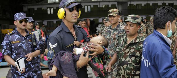 Um militar da Força Aérea da Índia socorre uma criança no Nepal. - Sputnik Brasil
