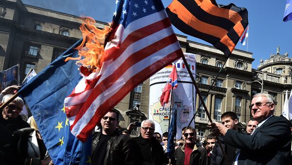 O político nacionalista sérvio Vojislav Seselj cercado por seus apoiadores mantém uma  bandeira da OTAN durante uma manifestação de oposição ao governo (foto de arquivo - 2015). - Sputnik Brasil