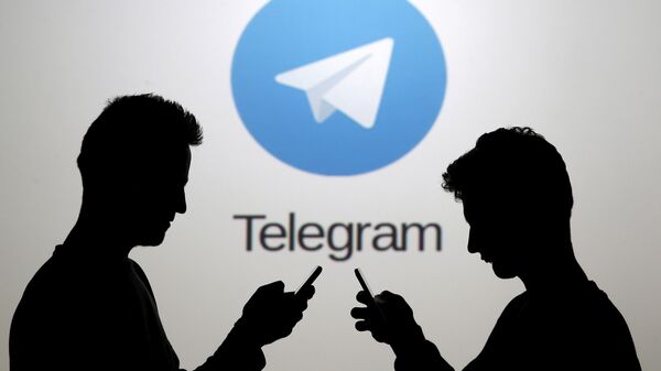 Dois homens usando seus smartphones estão em frente ao logotipo do Telegram. - Sputnik Brasil