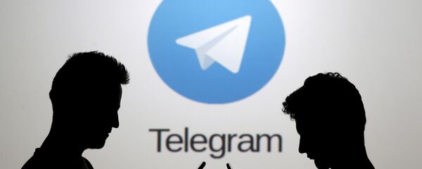 Dois homens, usando seus smartphones, estão em frente ao logotipo do Telegram - Sputnik Brasil