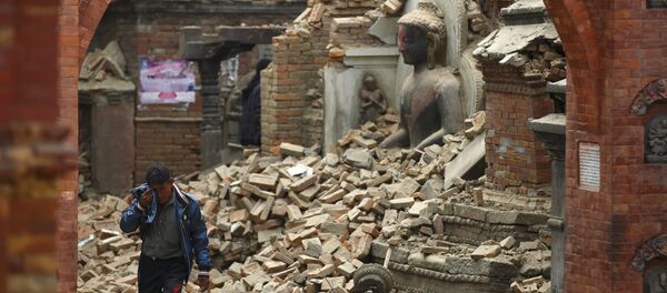 Homem chora enquanto passa ao lado de uma estátua de Buda danificada pelo terremoto no Nepal - Sputnik Brasil