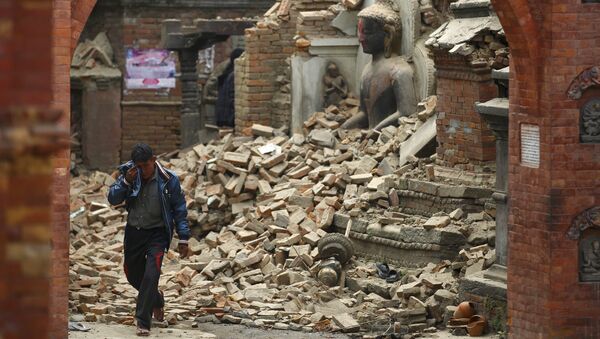 Homem chora enquanto passa ao lado de uma estátua de Buda danificada pelo terremoto no Nepal - Sputnik Brasil