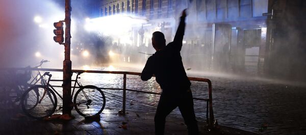Manifestante joga uma garrafa contra a polícia de choque durante manifestações na cúpula do G20 em Hamburgo Manifestante joga uma garrafa contra a polícia de choque durante manifestações na cúpula do G20 em Hamburgo - Sputnik Brasil