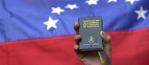 Um manifestante segurauma cópia em miniatura da constituição da Venezuela em frente à bandeira da nação durante uma manifestação do governo em Caracas, Venezuela, terça-feira, 13 de abril de 2004 (foto de arquivo). - Sputnik Brasil
