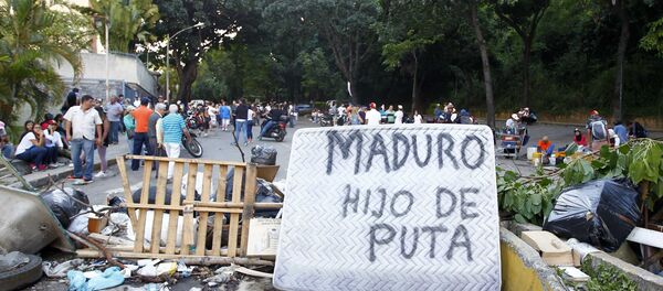 As pessoas passam por uma barricada de rua que inclui um colchão com as palavras Maduro filho da puta durante confrontos nas eleições da Assembleia Constituinte realizadas em Caracas, Venezuela, 30 de julho de 2017. - Sputnik Brasil